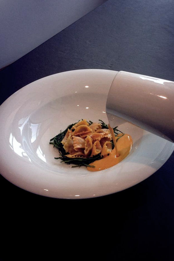 Creazione gourmet di Andrea Berton con pasta fresca e crema colata al momento, esempio della cucina italiana contemporanea.