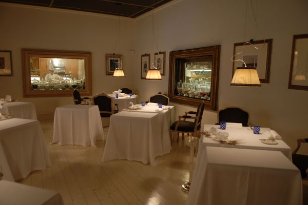 Sala ristorante di Casa Vissani con tovaglie bianche e ampie vetrate sulla cucina a vista.