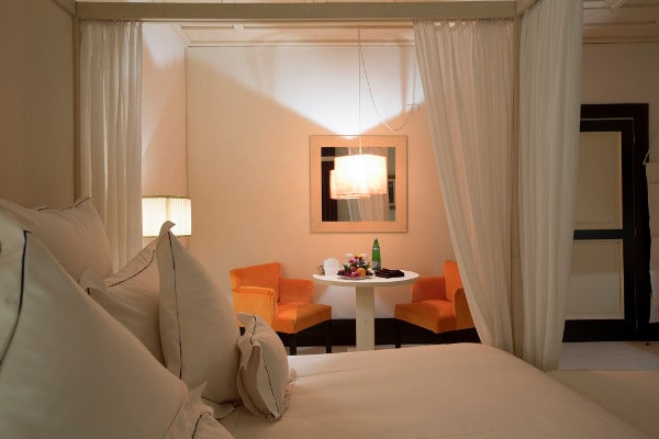 Camera elegante di Casa Vissani con letto a baldacchino e angolo relax arredato con poltrone arancioni.