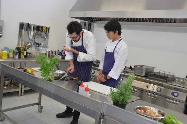 Dimostrazione pratica dello chef Fabrizio Ferrari in cucina con studente, corso di cucina professionale Agenzia Formativa Dante Alighieri.