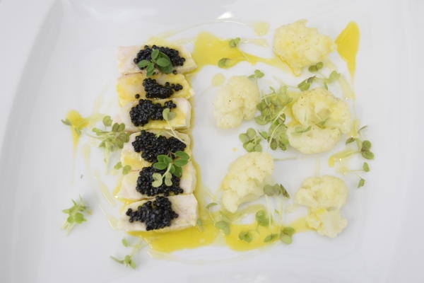 Filetto di pesce con cavolfiore e caviale su piatto bianco, creazione gourmet dello chef Gionata Bignotti.