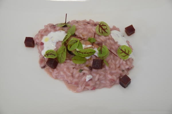Risotto rosa con barbabietola e guarnizione di erbe fresche, piatto dello chef Gionata Bignotti.