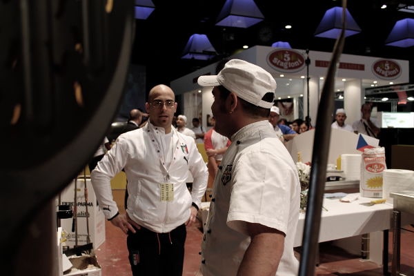 Giuseppe Lapolla con altri pizzaioli durante una competizione internazionale, riconoscibile dalla divisa con stemma Italia.