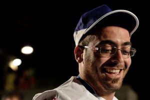 Primo piano sorridente del maestro pizzaiolo Giuseppe Lapolla con cappellino, campione del mondo e docente dei corsi per pizzaiolo presso Agenzia Formativa Dante Alighieri.