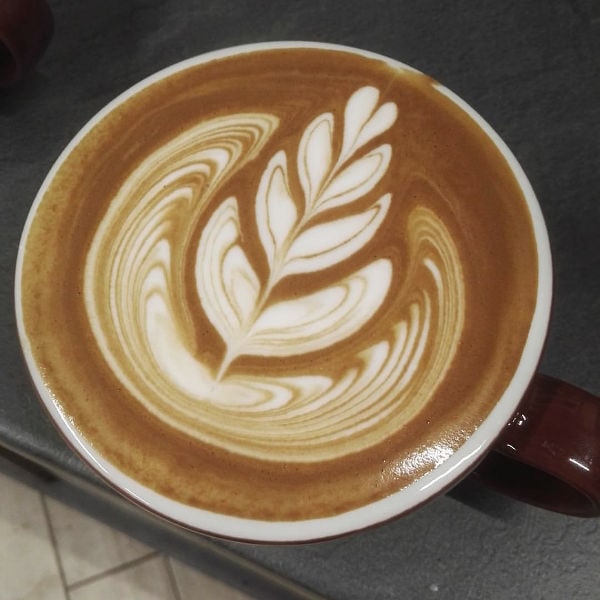 Cappuccino con latte art floreale a foglia realizzato da Matteo Beluffi con grande precisione.
